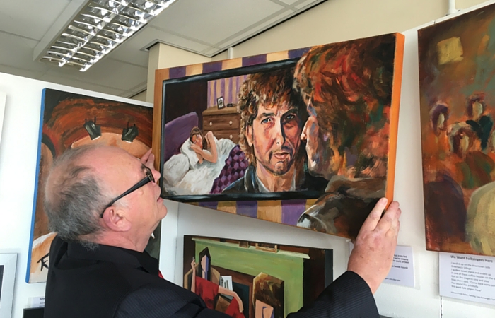 Artist Tony Kenwright hangs one of his works at his Visions of Bob Dylan exhibition at West Kirby Concourse